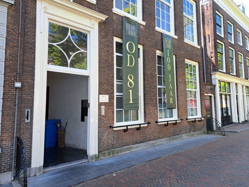 Gevel van Oude Delft 81, waar twee groene banieren aan opgehangen zijn met de tekst 